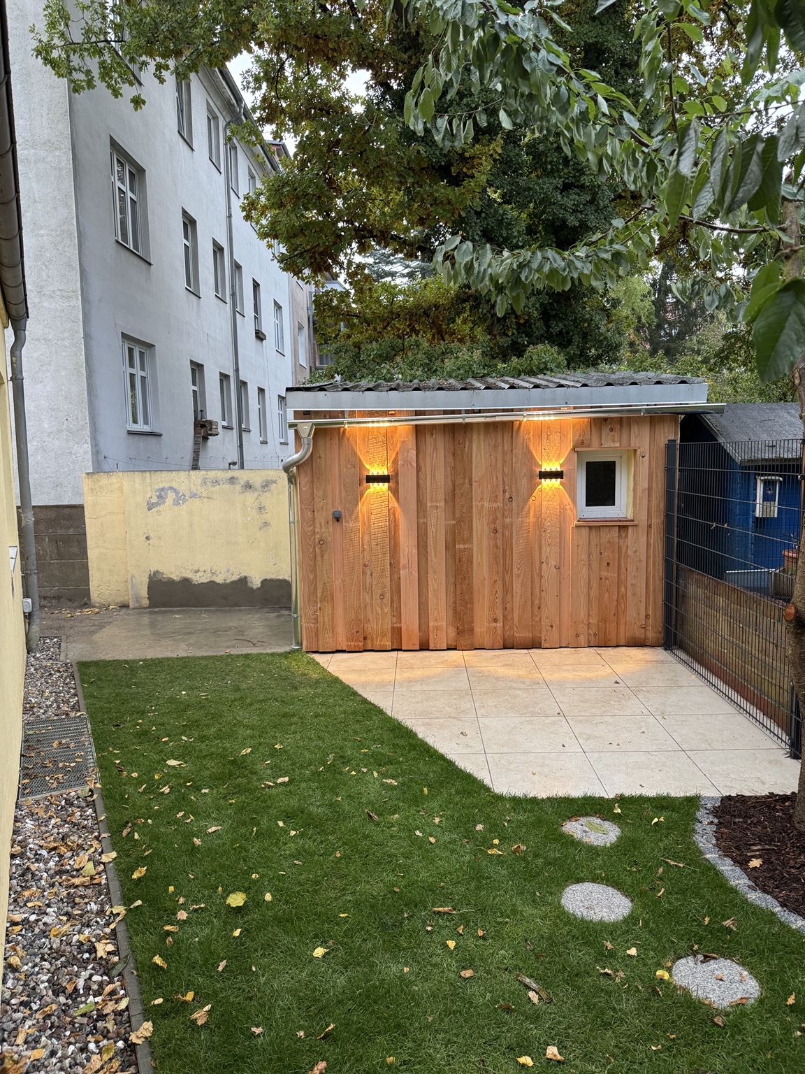 Holzgartenhaus mit Rasen und Trittplatten