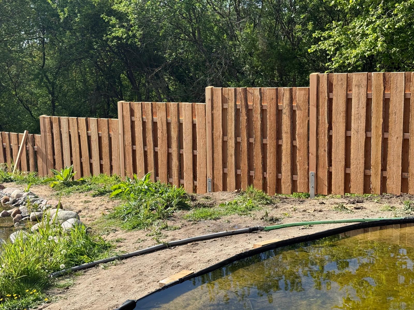 Gartenteich neben einem Holzzaun